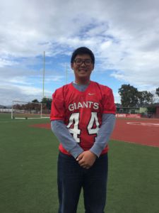 Sophomore Ethan Kim stands on the Redwood Football field, posing with his jersey.