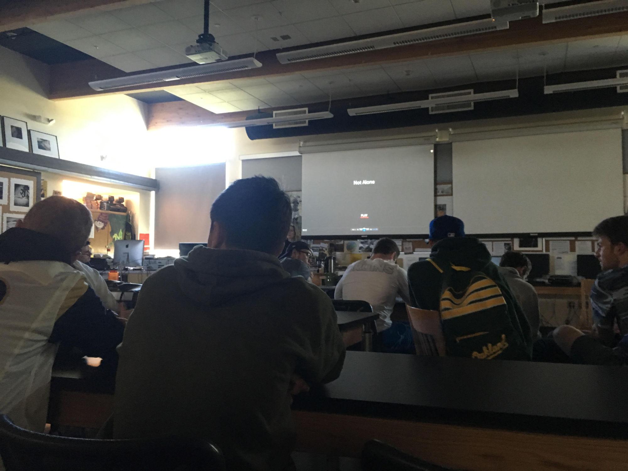 Students watch the screening of Not Alone in the Photo classroom