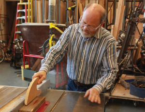 Demonstrating how to operate a saw in the shop, Esteb considers himself an artist, designer, architect, and builder.