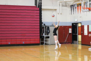 Serving the ball, volleyball player jumps high in the air. 