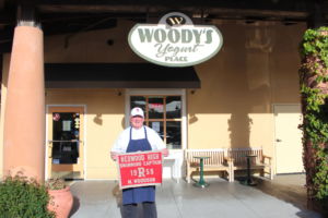 Standing in front of Woody's Yogurt Place, Michael Woodson holds his 1959 varsity swim team captain's flag.