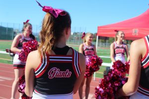 Cheerleaders support the football team in uniforms they fundraised for themselves.