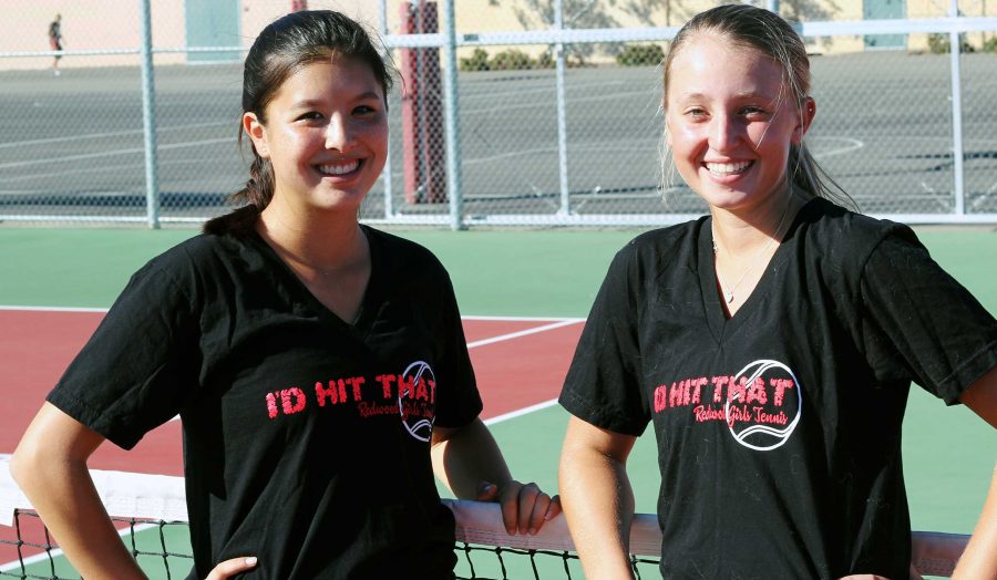 Sophia Hooper, senior, and Lauren Wolfe, freshman, pose in the tennis practice t-shirts that were banned from school grounds. The t-shirt says “I’d hit that.”