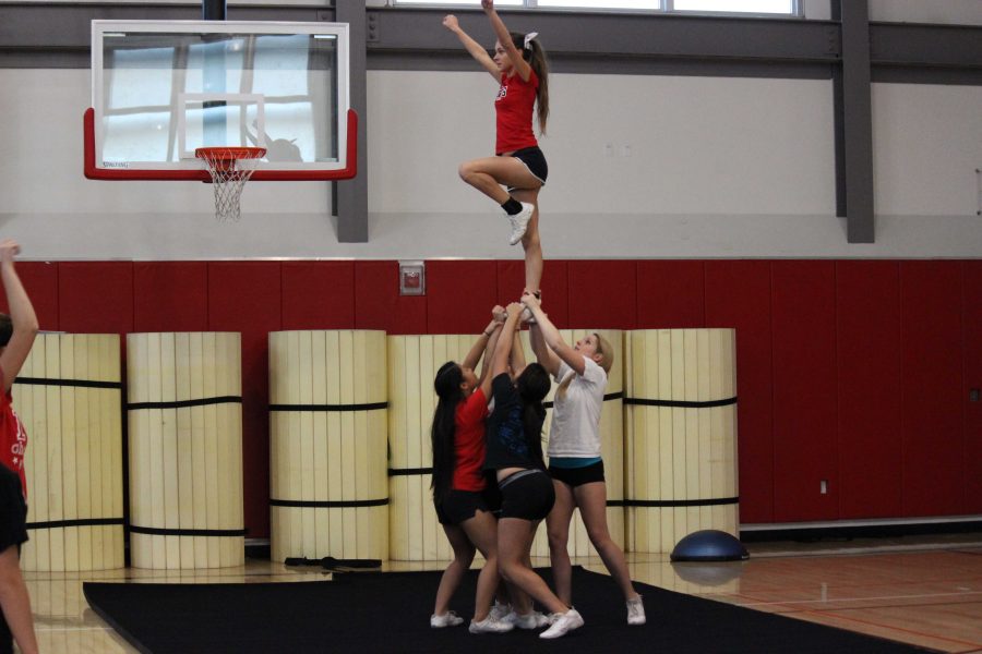 Cheerleaders practice their routine during a practice in the small gym.