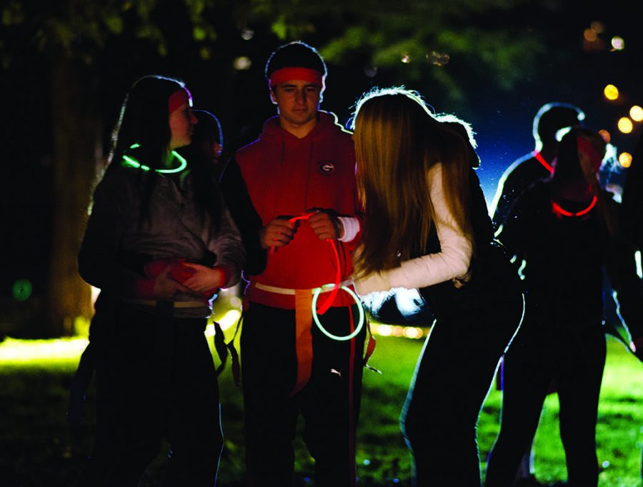 JOSE LASSEN-BAEZA, junior, and others prepare for a night game of capture the flag hosted by Friday Night Live by equipping themselves with glow sticks.