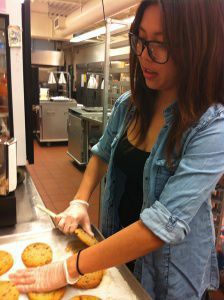 JUNIOR LILY LE PREPARES lunch for students. She works in the cafeteria five days a week on top of several other jobs and responsibilities.