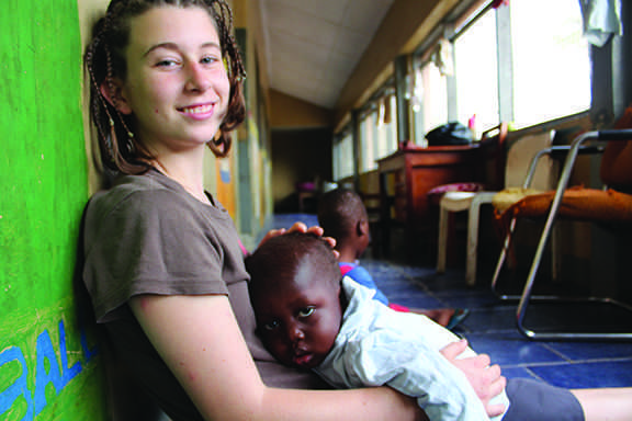 Holding malnourished three-year-old KeKe on her lap, sophomore Kelly McCormish, dedicated her summer to volunteering in an orphanage in Africa