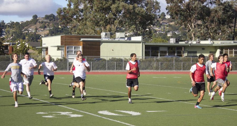 The boys soccer team runs on the turf field during the fall.