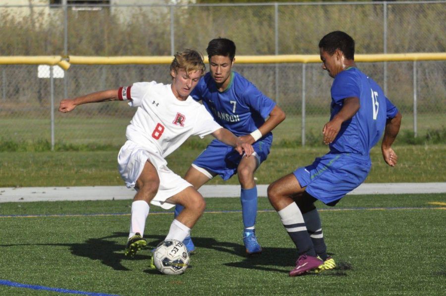 Captain Isaac Perper defends the ball from two Branson opponents. 