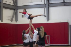 Junior Jenna Hassell practices cheer position during practice.