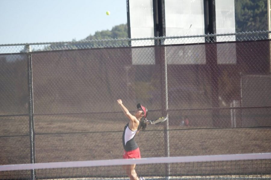 Varsity tennis player winds up, read to propel approaching ball forward. 