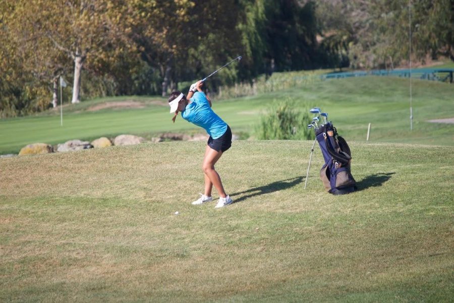 Junior Kendra Loo follows through on her swing during the match at McInnis Park Golf Center against Drake. 