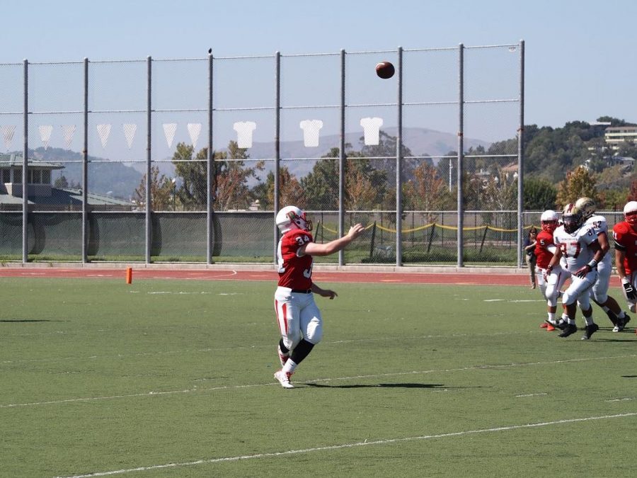 Varsity football player runs to  catch the pass. 