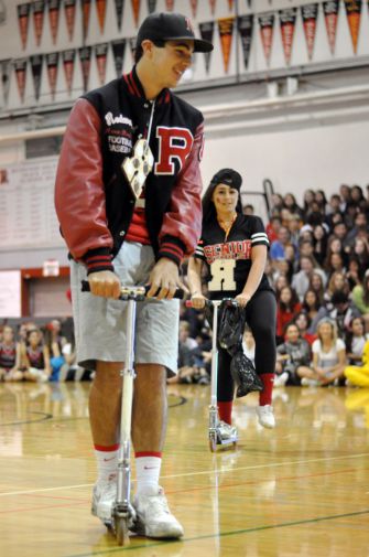  Aaron Dorfler and Danielle McCauley ride around the gym on scooters as Mr. Dibley announces their accomplishments.