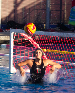 Junior goalie Laurel Doyle springs up out of the water, preparing to block the shot. 