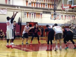 The boys' varsity basketball team watches as a Redwood alumni takes a free throw. 