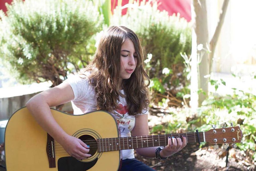 Sophomore Noa Zimmerman plays guitar outside of the school. Zimmerman recently published her second album titled, “The Logic in Your Flaw.”