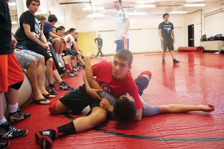 Sparring on the mat against teammate Same Miranda, sophomore Simon Ermolov practices in front of fellow varsity wrestling members. Ermolov placed third in MCALs in the 128-pound weight class last year. 