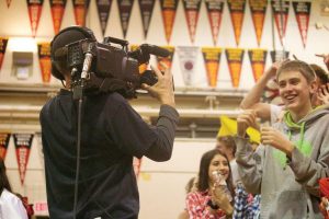 Both the boys' and girls' varsity basketball games were filmed by Comcast Hometown Network at last Friday's game night. Here, sophomore Cody Meylan cheers while a cameraman approaches the crowd.