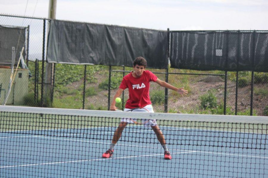 Senior Nic Barretto practices his backhand while playing against his brother Paull