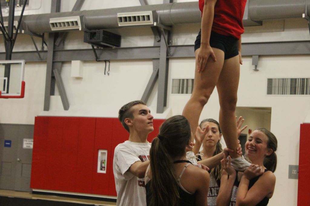 Freshman Max Dostal helps  teammates stunt during practice