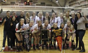 The girls' varsity volleyball team poses with the NCS DII championship banner, the NCS DII plaque, and the MCAL championship banner(From left to right).