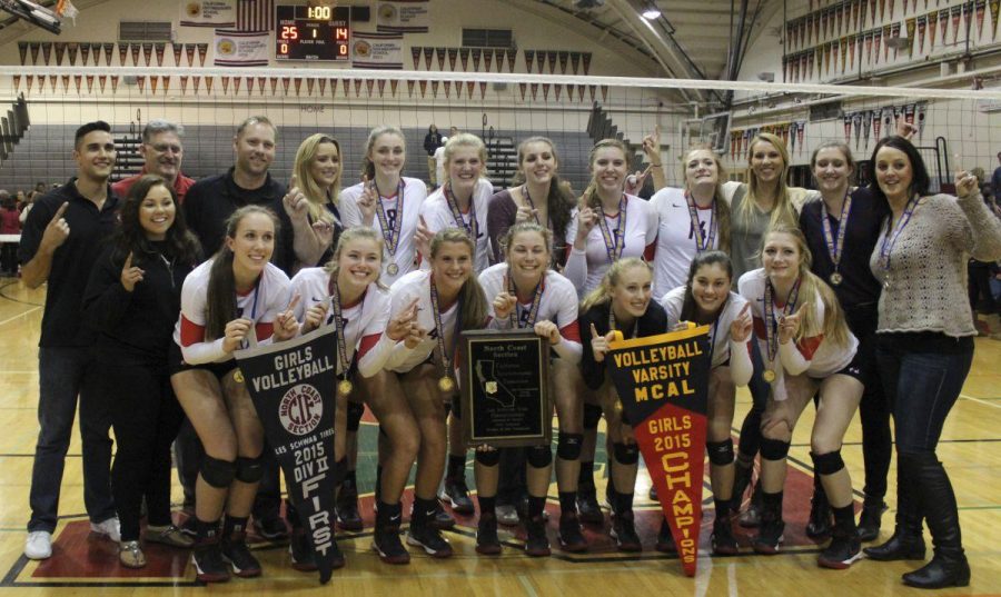 The girls varsity volleyball team poses with the NCS DII championship banner, the NCS DII plaque, and the MCAL championship banner(From left to right).