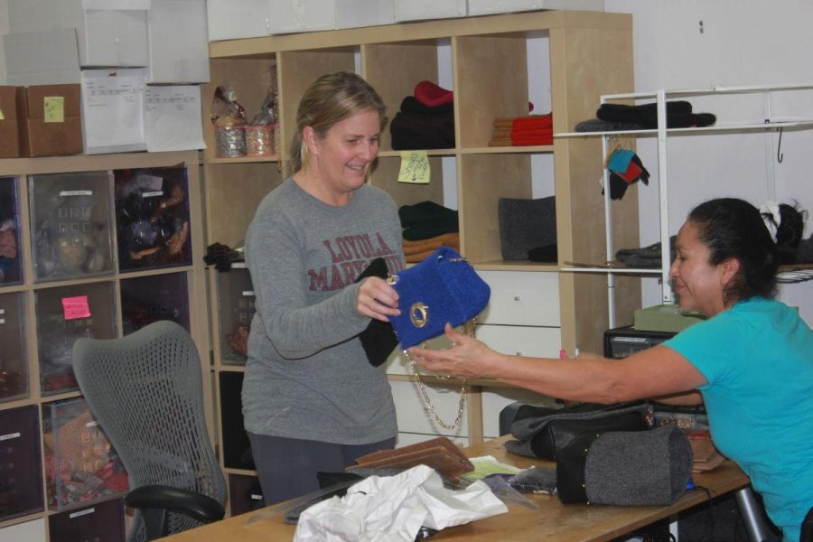 Entrepreneur Sarah Oliver passes a completed handbag to one of her employees. Sarah Oliver handbags are knitted by senior citizens of the Redwoods Retirement Community and customized with either a gold or silver brooch. 