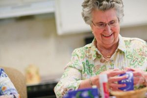 Participating in arts and crafts, an elderly resident engages in activities that are led by student volunteers such as Lindsey Papuc at Aegis Living in Corte Madera.