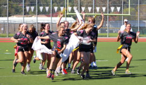 The 2017 senior girls team runs through their banner before the start of the Klassy Kickoff flag football game.
