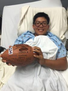 Pictured holding a football signed by his teammates, Kim regains some courage during his time at the Marin General Hospital. (Photo courtesy of Ethan Kim) 