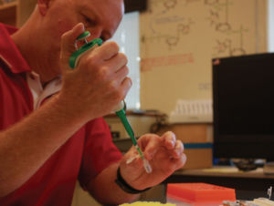 Focusing on the task at hand, Lovelady transfers liquids using a micropipette and other lab equipment 
