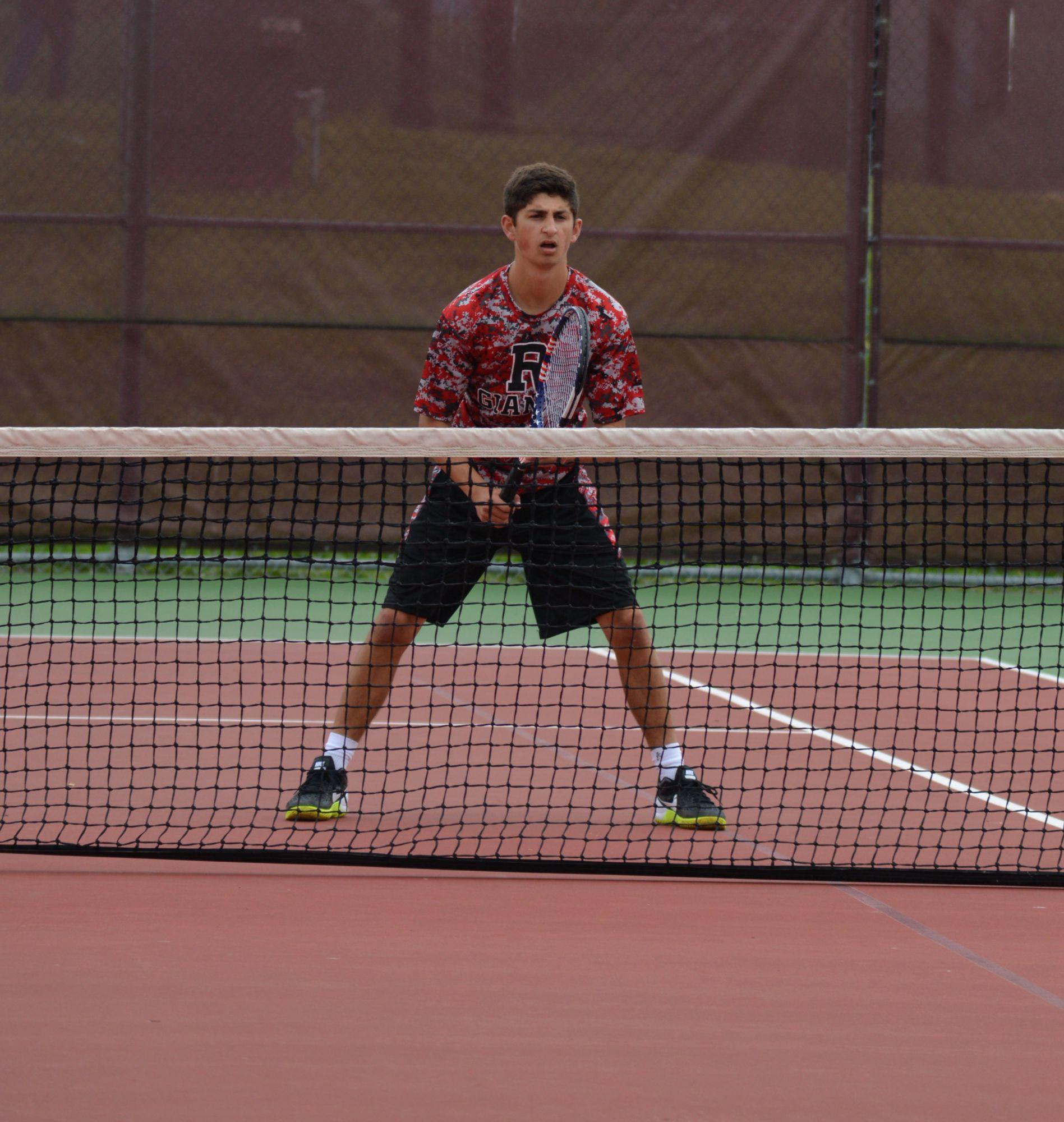 Senior Zach Babikian peers over the net during the team's playoff matchup against Branson.