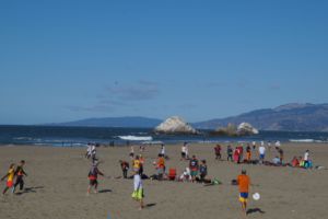 A multitude of people enjoy activities on the beach as the RHS Surfrider Club partakes in community service. 