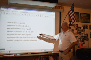 Leading a lecture in his economics class, computer graphics, economics and government teacher William Crabtree highly values corporate trust and discusses it with his students.
