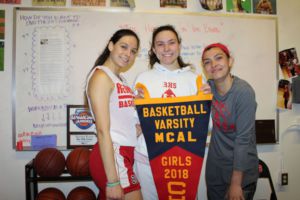 Grasping onto their MCAL pennant, the varsity captains smile excitedly.