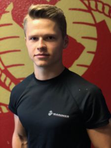 United States Marine Corps recruit senior Oliver Bagshaw wearing his official Marine Corps t-shirt in front of The Eagle, Globe and Anchor official emblem of the Marine Corps.