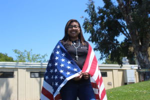 United States Marine Corps recruit senior Andrea DeLeon poses in an official Marine Corps t-shirt with an American flag draped over her shoulders.