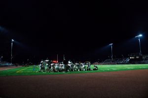 The stadium lights shine down onto the Redwood Giants during their halftime talk