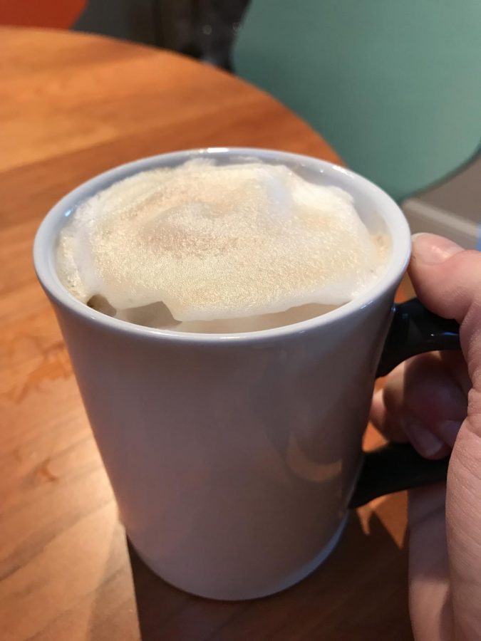 A server prepares a latte for a waiting customer