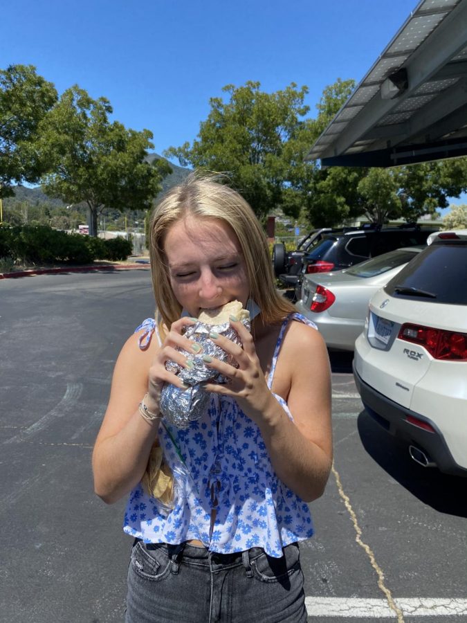 Senior Courtney Carlisle takes a generous bite out of a burrito provided by leadership as part of “Senior Week”.