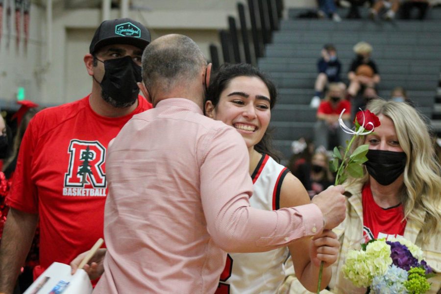 Smiling over her coach's shoulder, senior Lena Shuwayhat takes her rose and flowers.