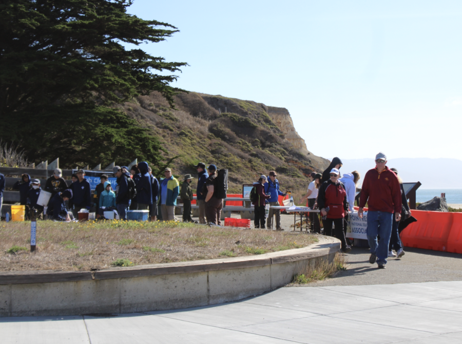 Gathering at the registration table, volunteers line up prior to partaking in a beach cleanup.
