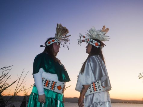 Facing each other, two of the dancers pose in front of the sunrise for a photo after completing their dance. 
