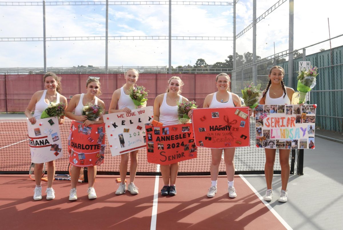 Seniors Kelly Melbardis, Charlotte Brod, Seriana Katz, Annesley Krawitt, Harriet Condos and Lindsay Reed smile with their senior day posters made by their teammates. (Photo by Katie Delsol)