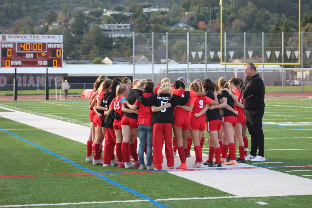 The Redwood girls’ varsity team is in a huddle before the game begins.
