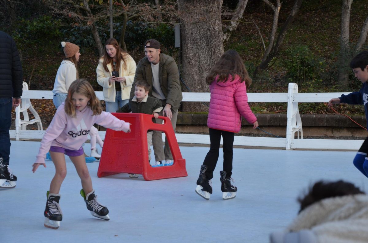 Laughing as they learn to skate, kids glide around the rink with their parents. 