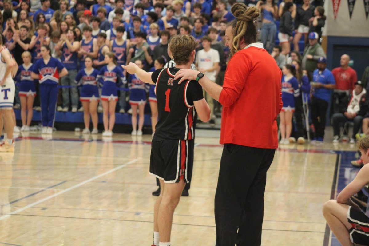 Strategizing with his coach, Brennan Woodley points towards the court. 
