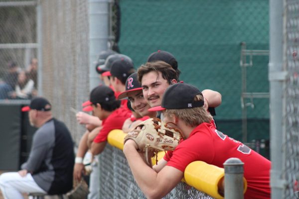 Smiling at the camera, juniors Miles Harrison and Matthew Knauer stand over the railing in between innings.
