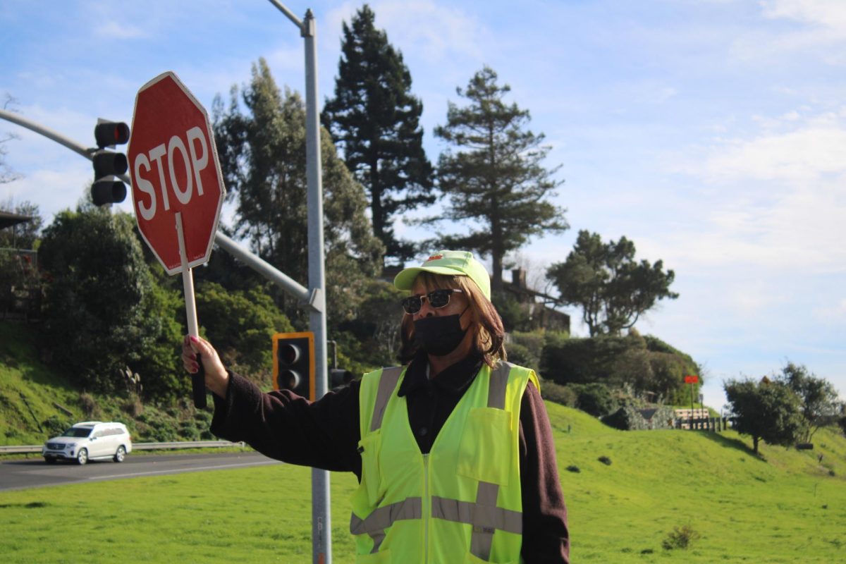 Wearing a bright yellow vest, Ms. Evie stands at the intersection of Trestle Glen in Tiburon, Calif. 